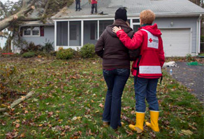 Red Cross and homeowner standing in front of damaged home after Hurricane Sandy
